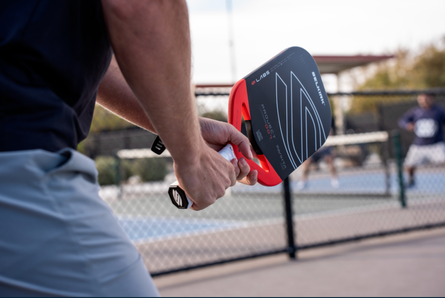 A man plays with the LABS Project 007 pickleball paddle on an outdoor court. 